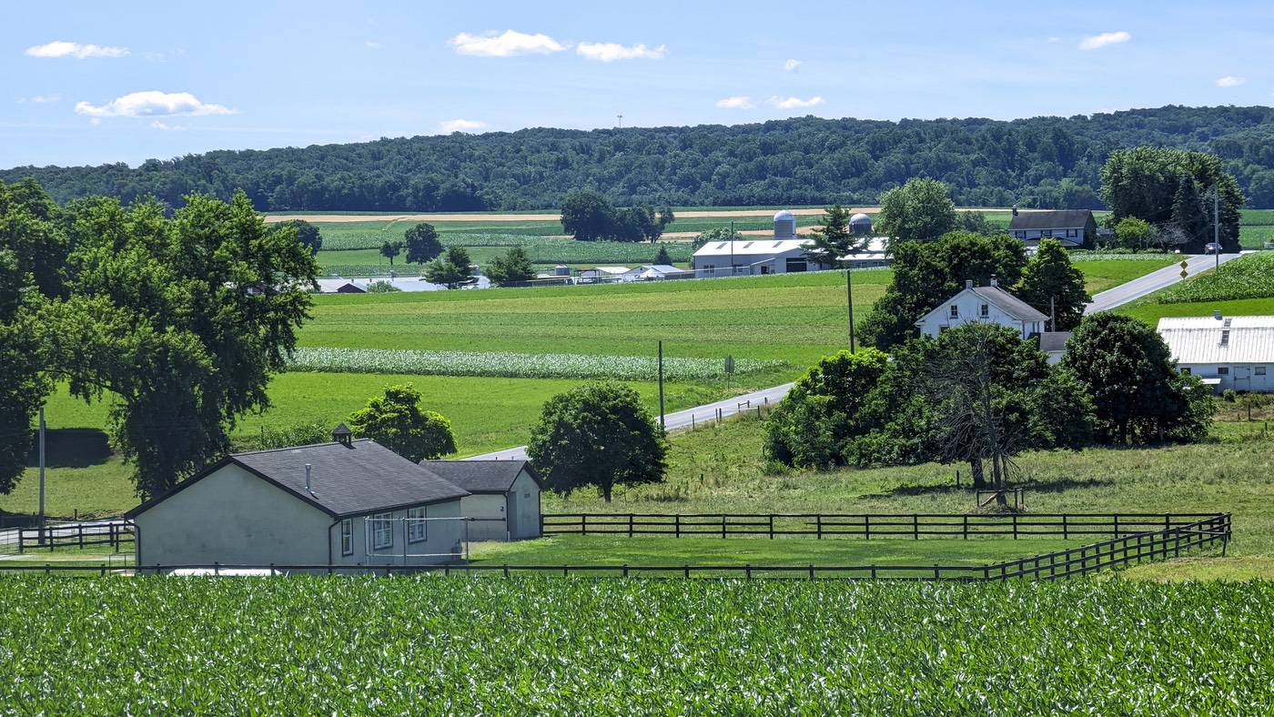 Scenic rural landscape with open fields and a farmhouse.