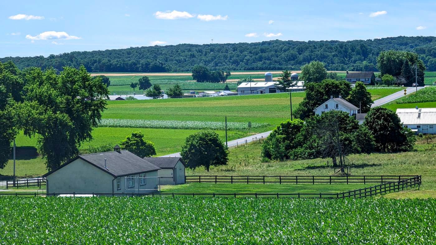 Scenic rural landscape with open fields and a farmhouse.