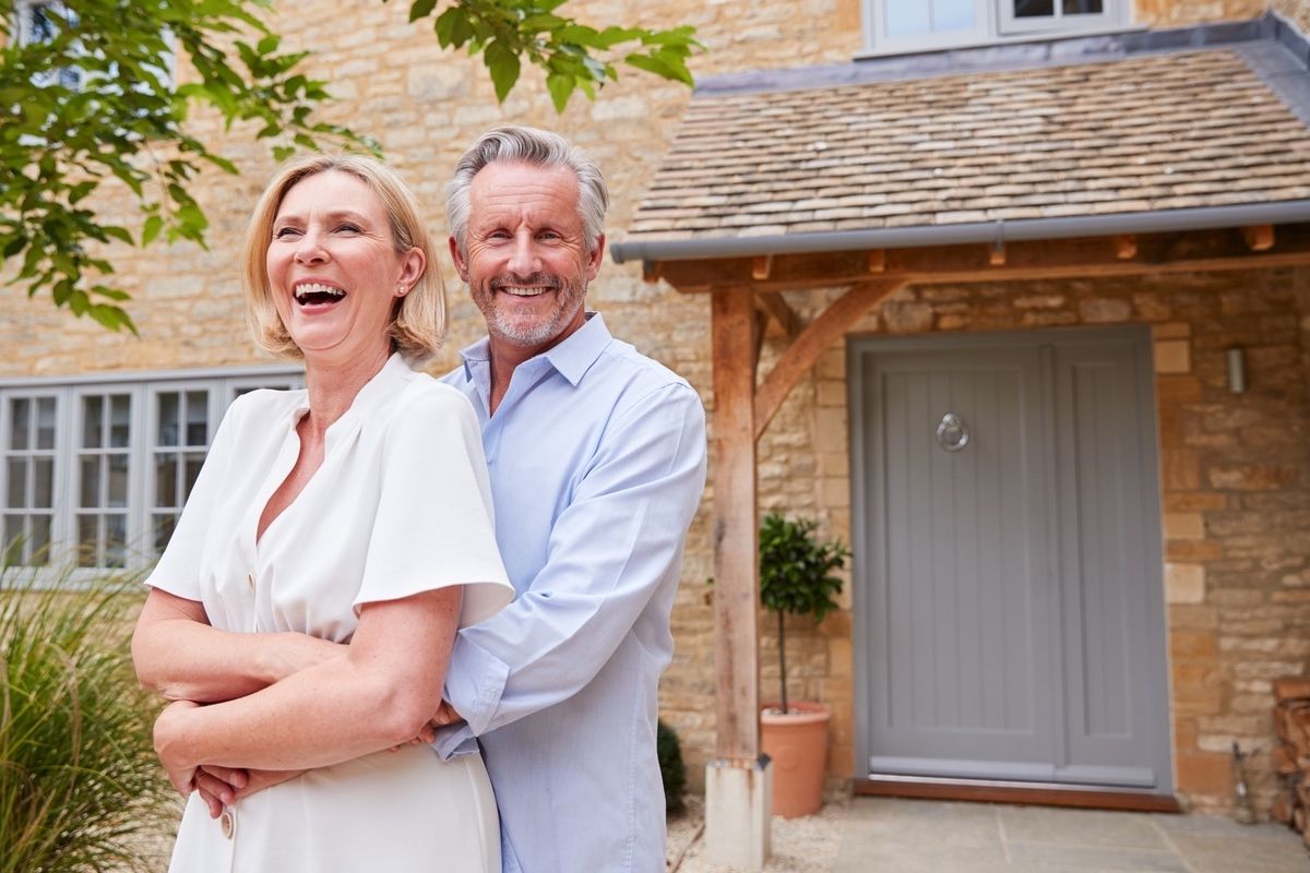 Smiling senior couple standing outside an accessible home entrance.