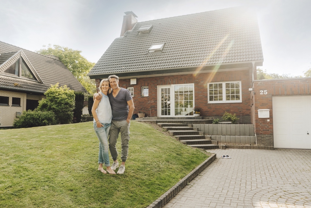 Homeowners embracing in their garden after refinancing success.