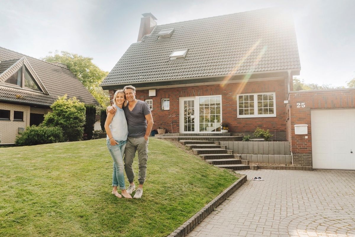 Homeowners embracing in their garden after refinancing success.